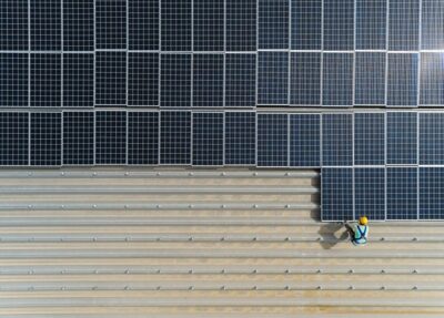 top view worker installing a solar cell on the factory roof.